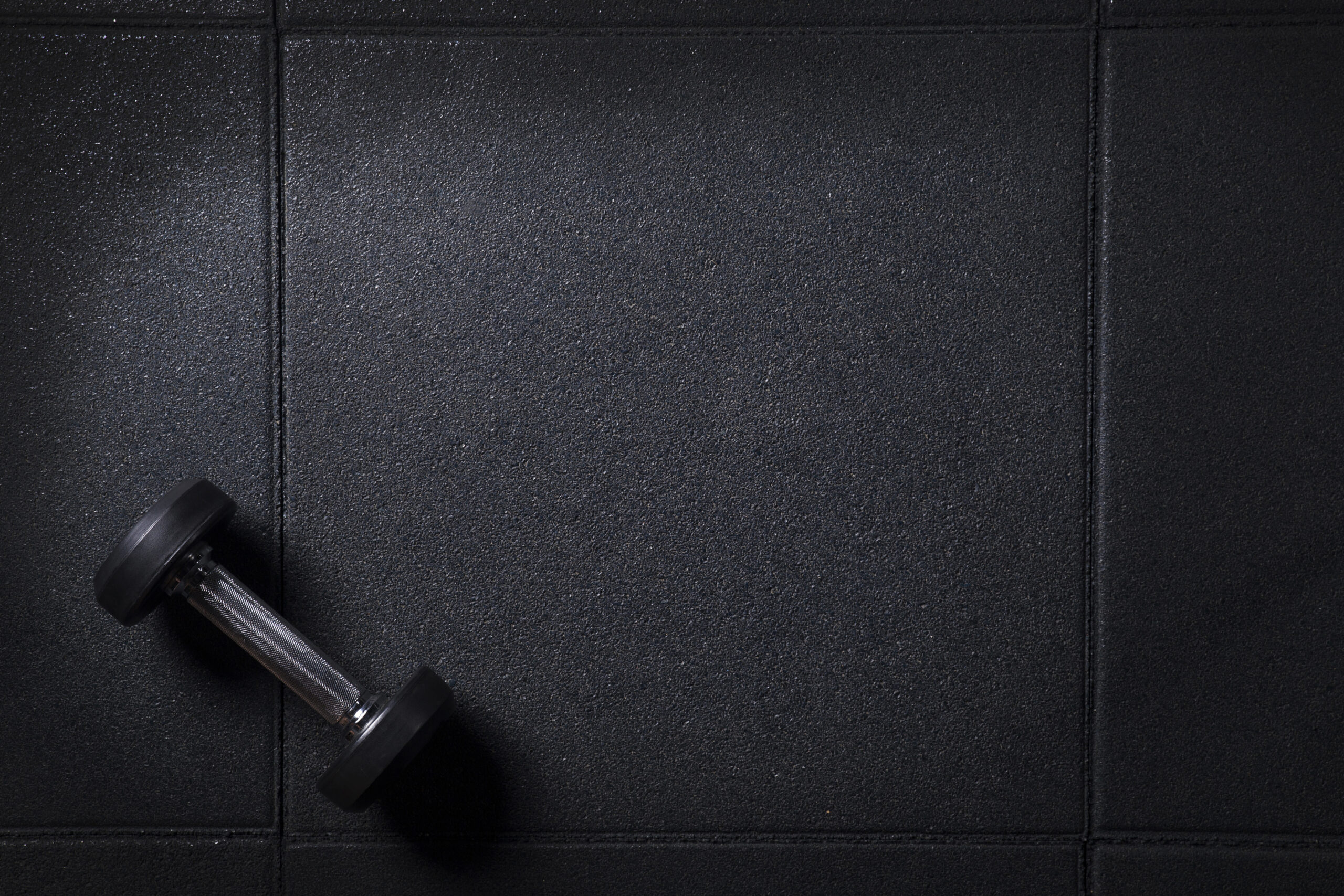 Dumbbell placed on black exercise mat